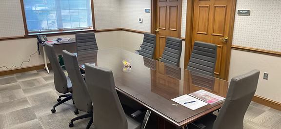 A conference room with a long table and chairs.