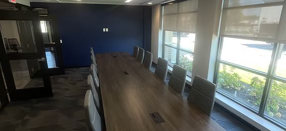 A conference room with a long table and chairs and lots of windows.