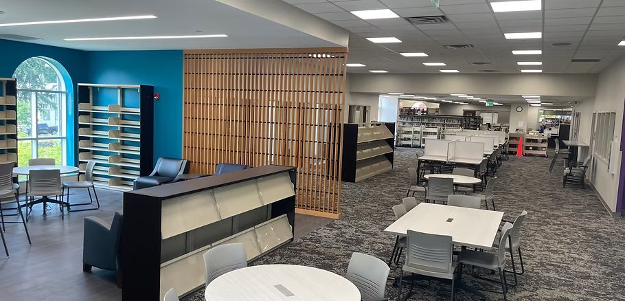 A large room with tables and chairs in a library.