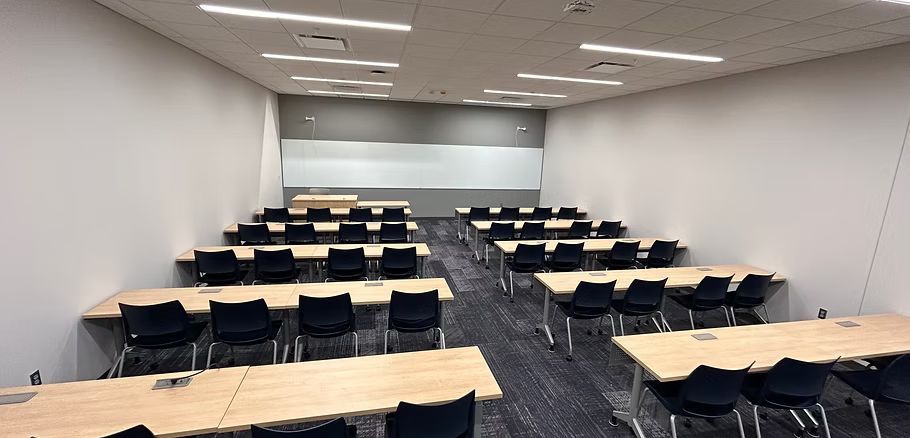 A large classroom with rows of tables and chairs.