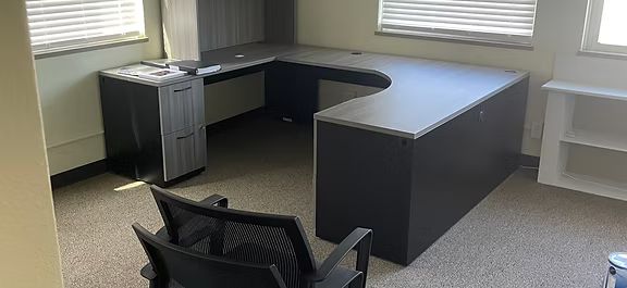 An empty office with a desk and chair in it.