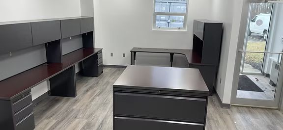A room with a lot of desks and drawers and a window.