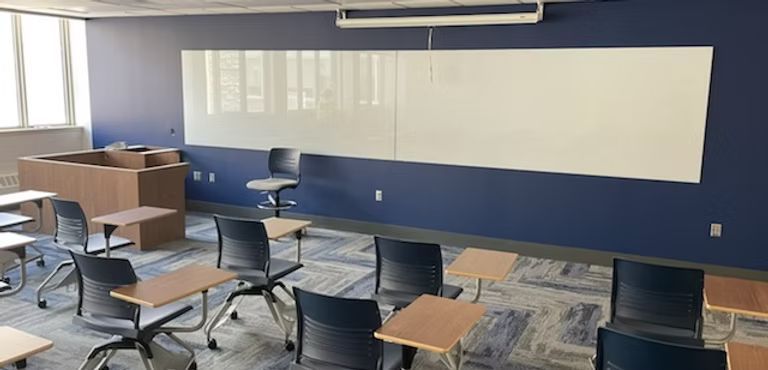 A classroom with tables and chairs and a whiteboard.