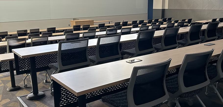 A row of long tables and chairs in a classroom.