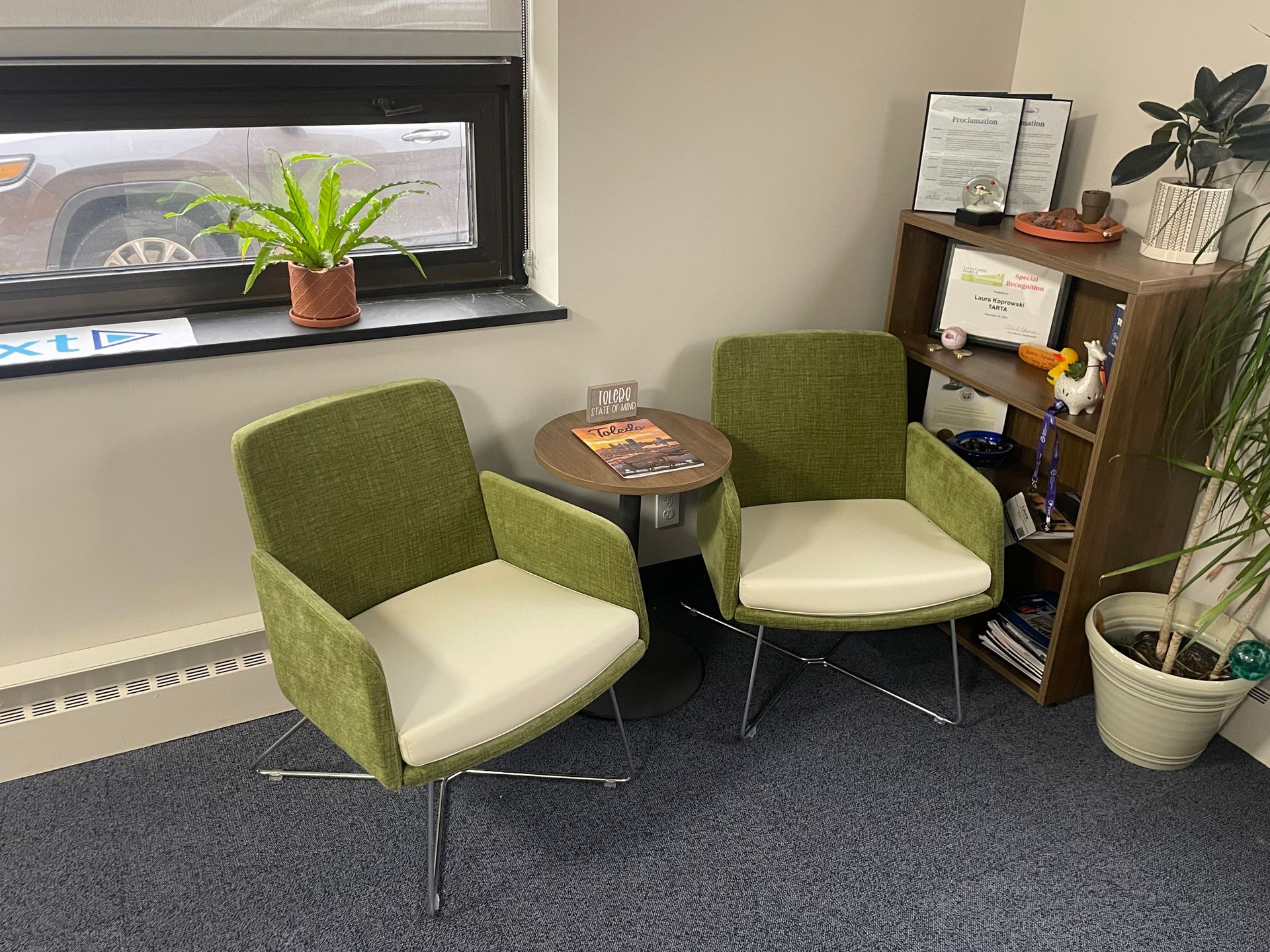 Two green chairs are sitting next to a small table in a room.