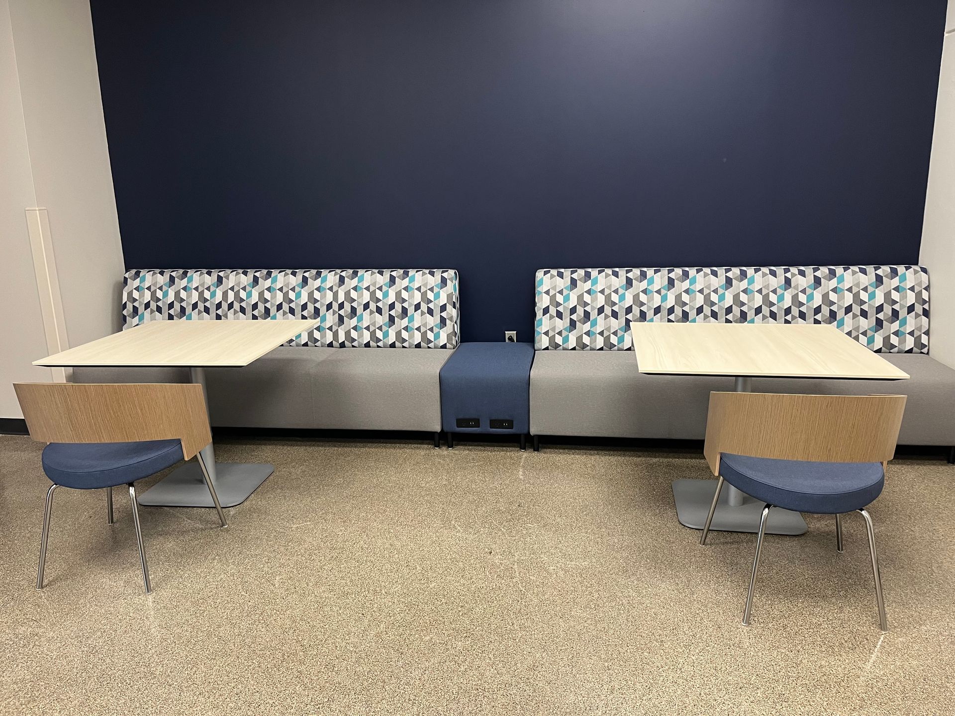 A room with tables and chairs and a blue wall.