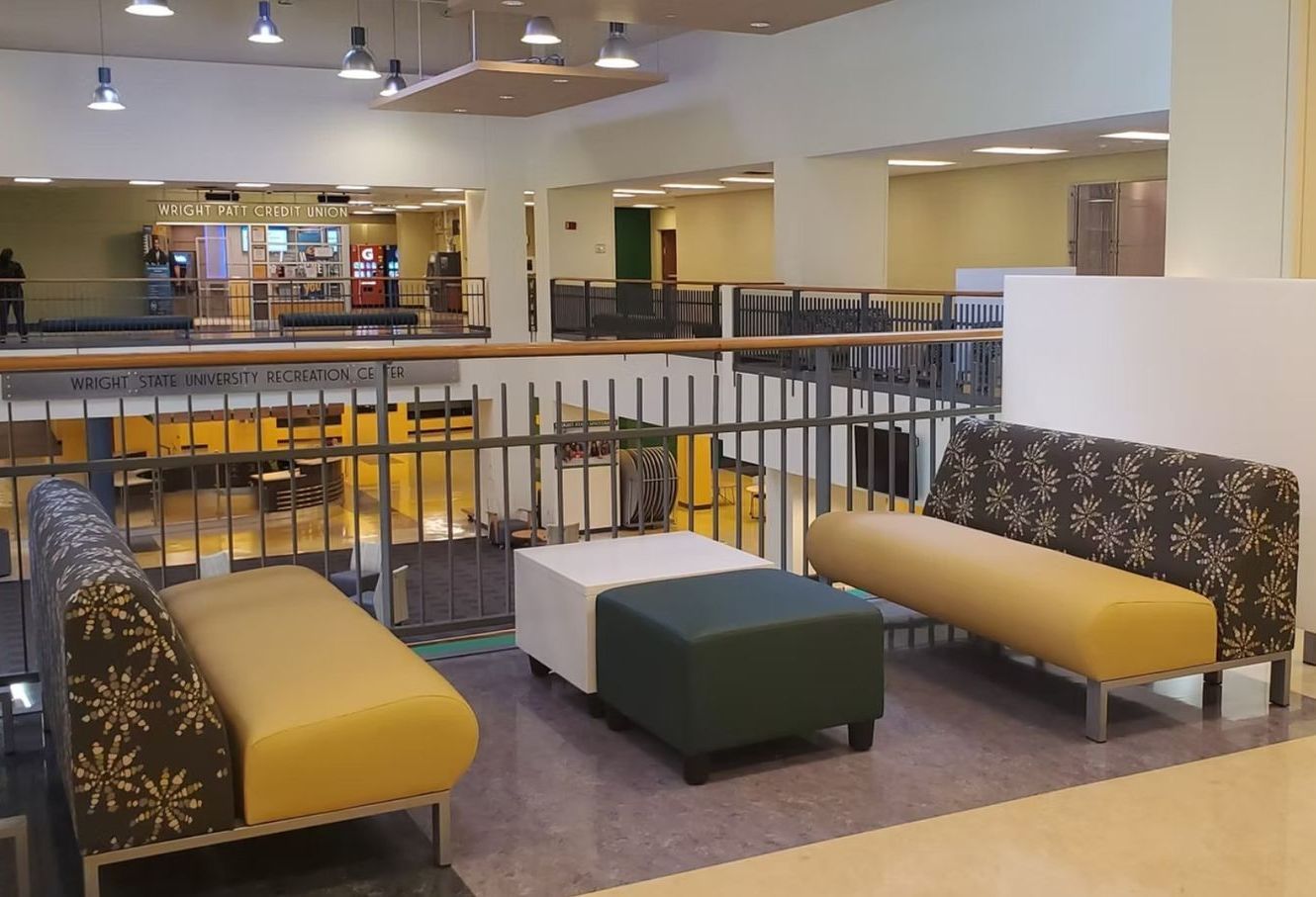 A waiting area with couch and ottomans in a building