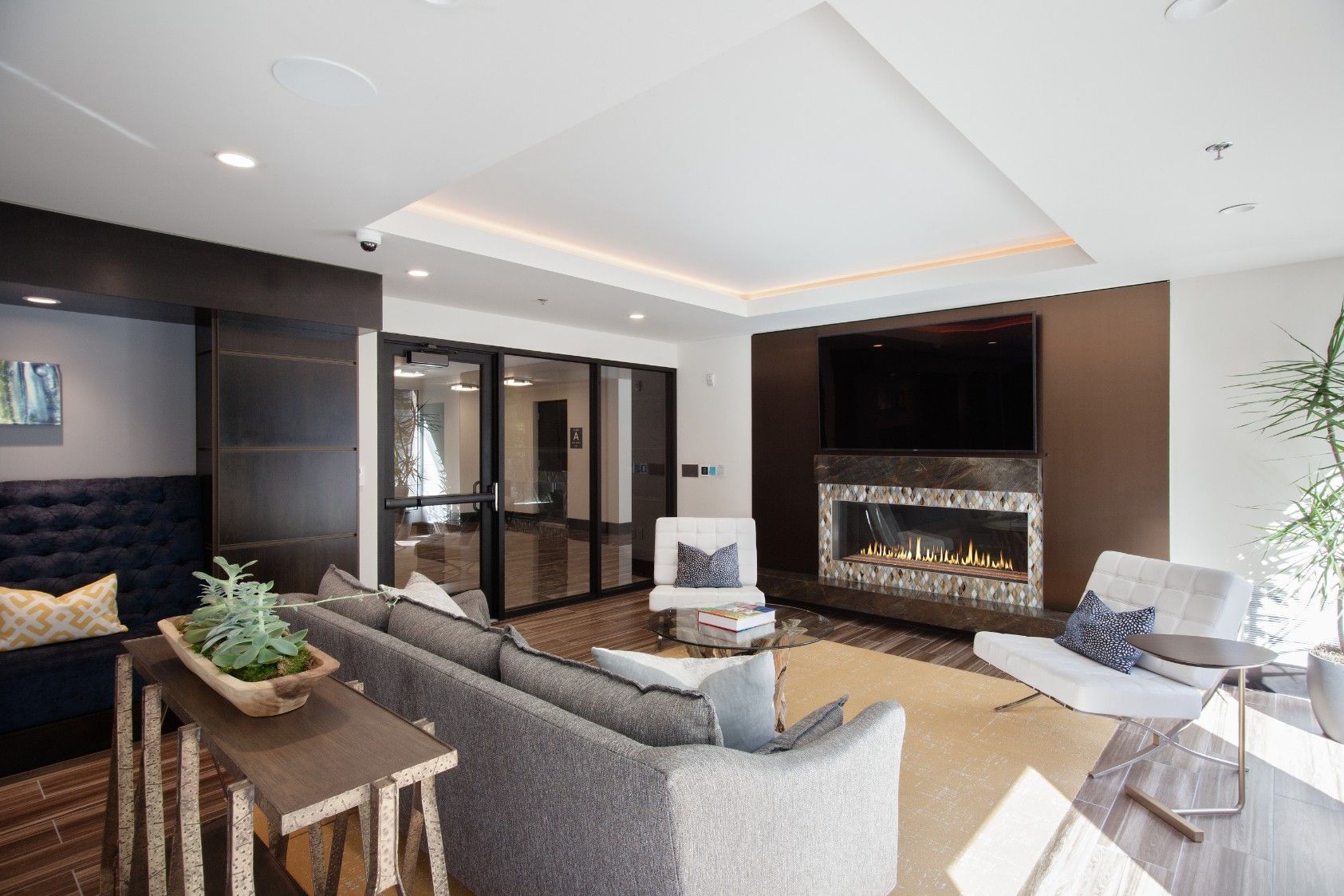 Modern living room with gray sofa, fireplace, wall TV, and bright windows