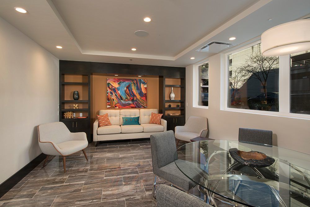 Modern living room with white sofa, patterned rug, glass table, wall art, and large windows