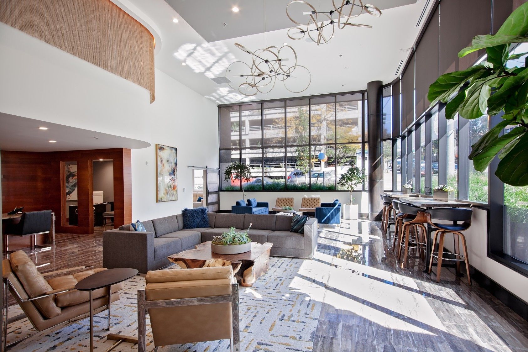 Bright hotel lobby with sofas, chairs, large windows, and a high ceiling with modern lighting