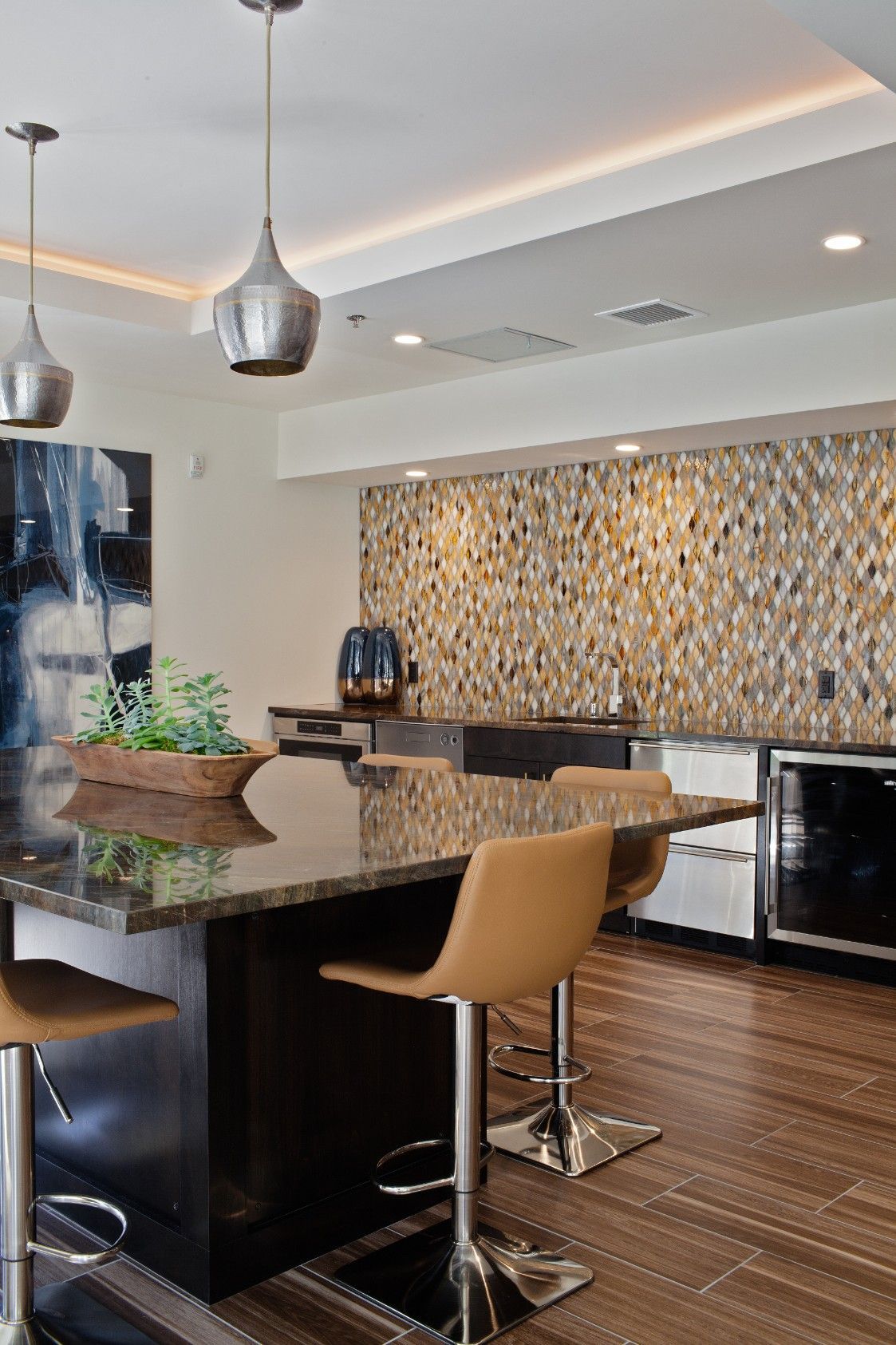 Modern kitchen with granite island, tan barstools, pendant lights, and mosaic backsplash