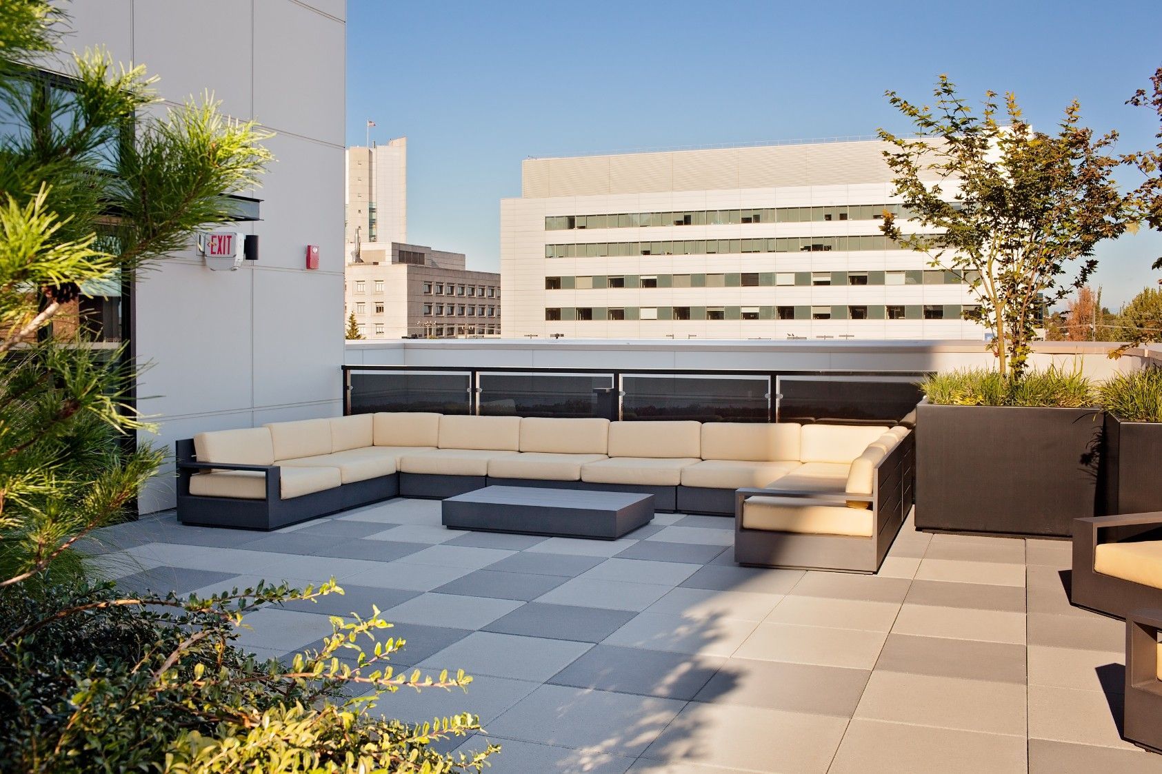 Modern rooftop patio with beige sectional seating and city buildings in the background