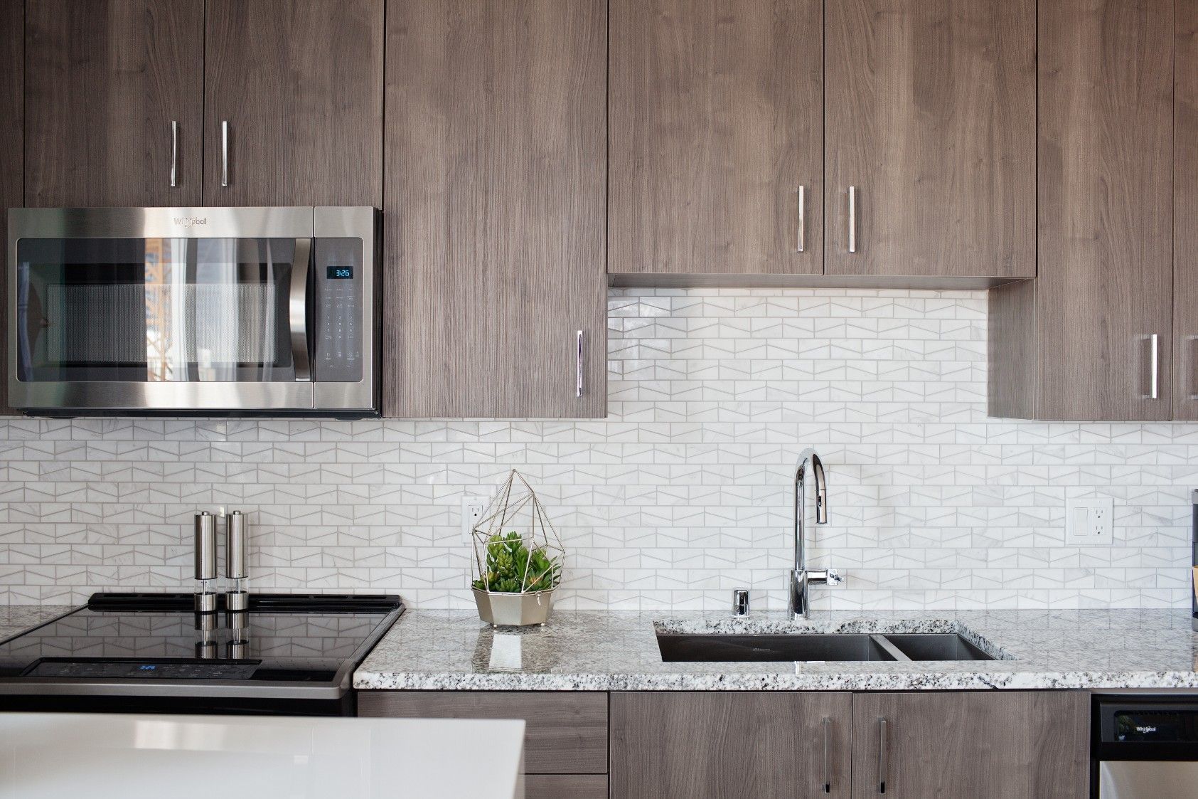 Modern kitchen with wood cabinets, stainless steel appliances, white tile backsplash, and granite countertop