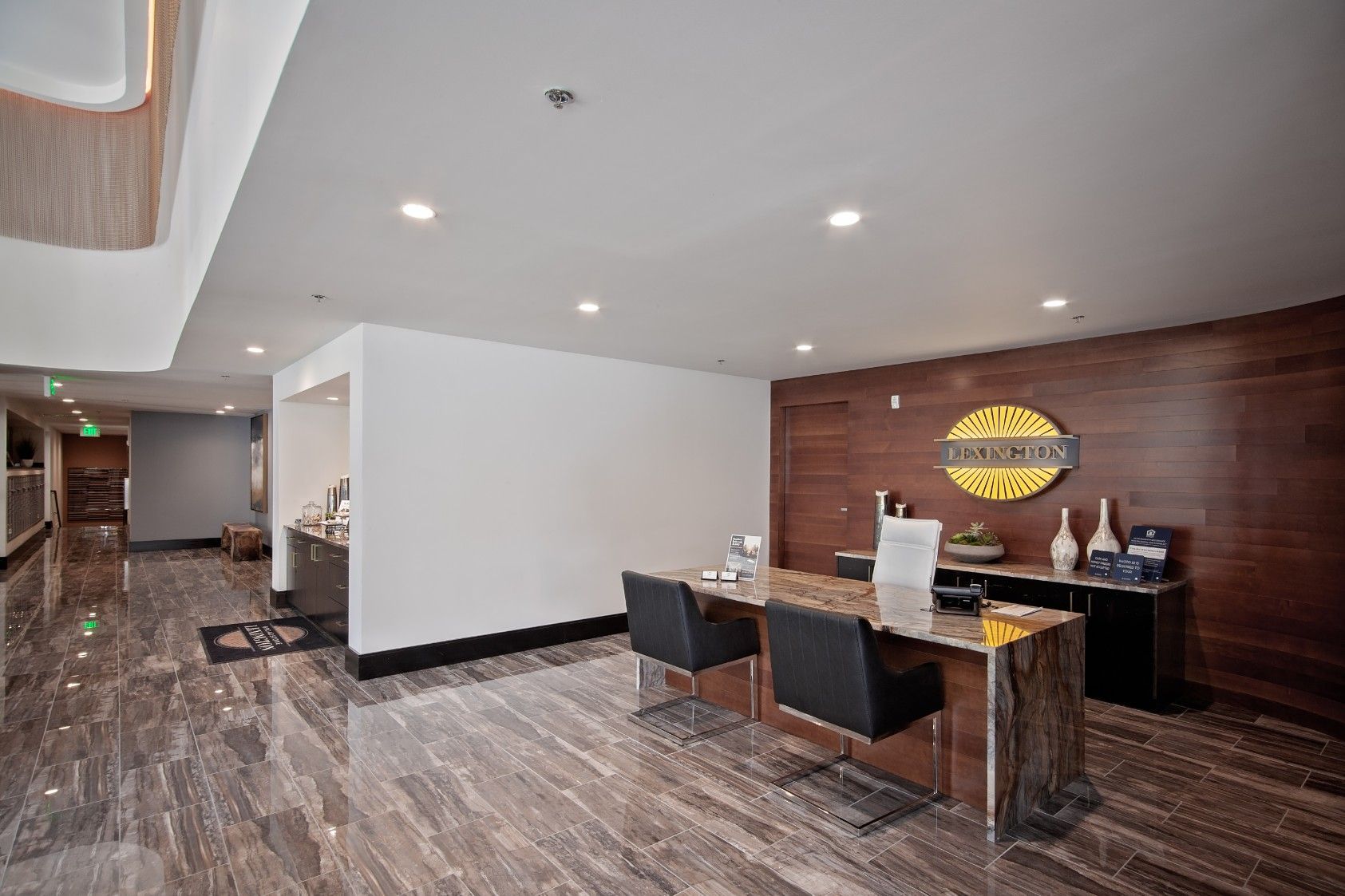 Modern hotel lobby with marble floor, wood accent wall, and a small seating area near a reception desk