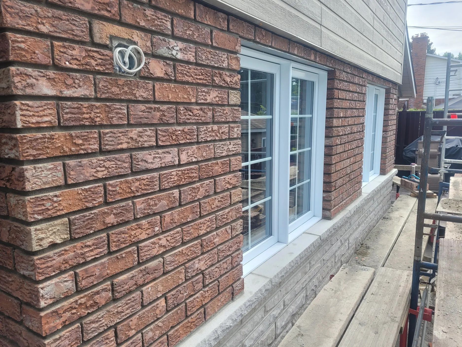 Un bâtiment en briques avec des fenêtres blanches et un échafaudage devant.