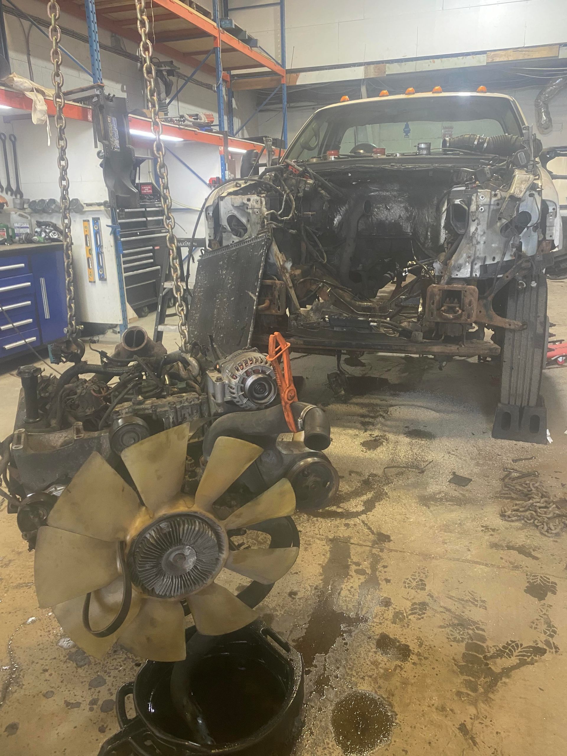 Le moteur d'un camion est en train d'être démonté dans un garage.