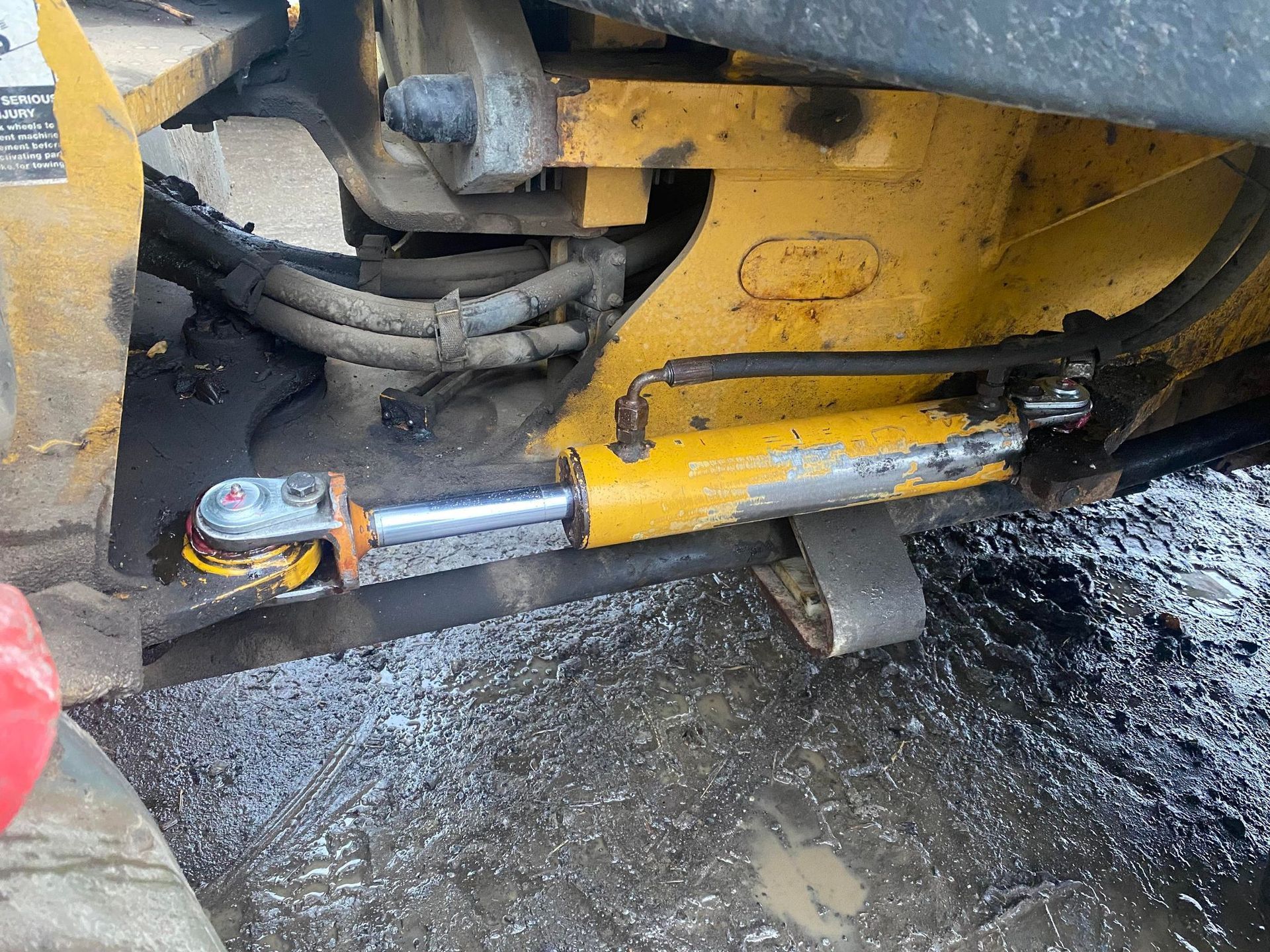 Un gros plan d'un vérin hydraulique sur un véhicule jaune.