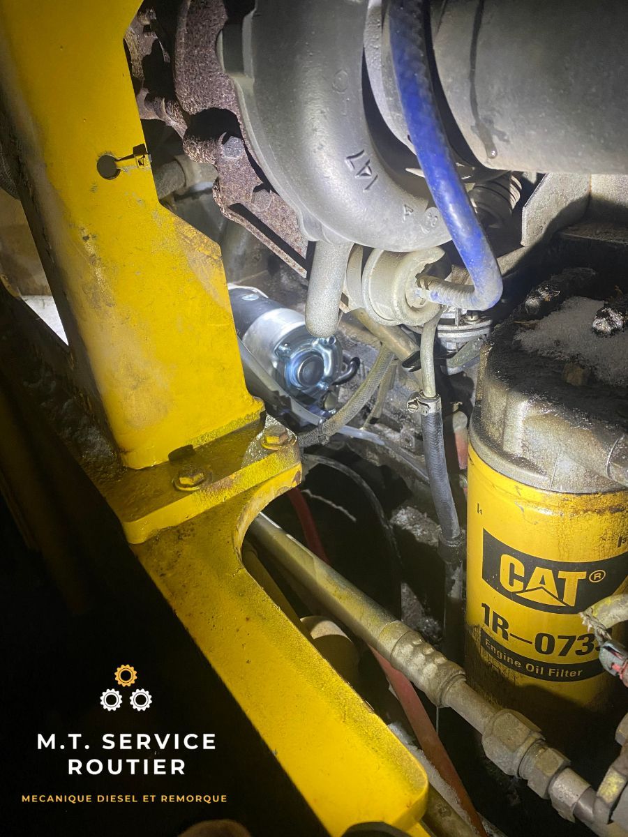 Un filtre à huile pour chat est posé sur un moteur jaune.