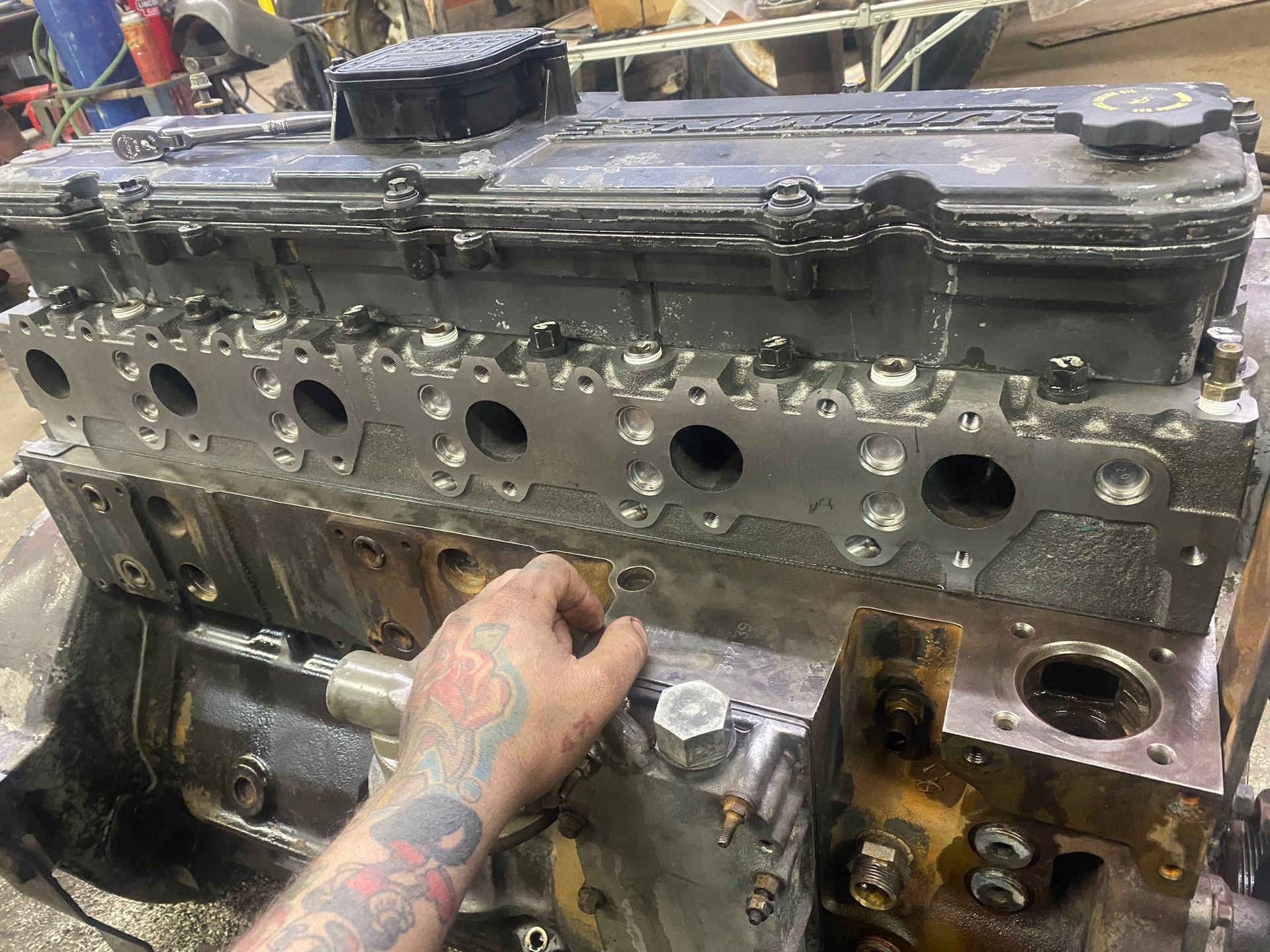 Un homme avec un tatouage sur le bras travaille sur un moteur diesel.