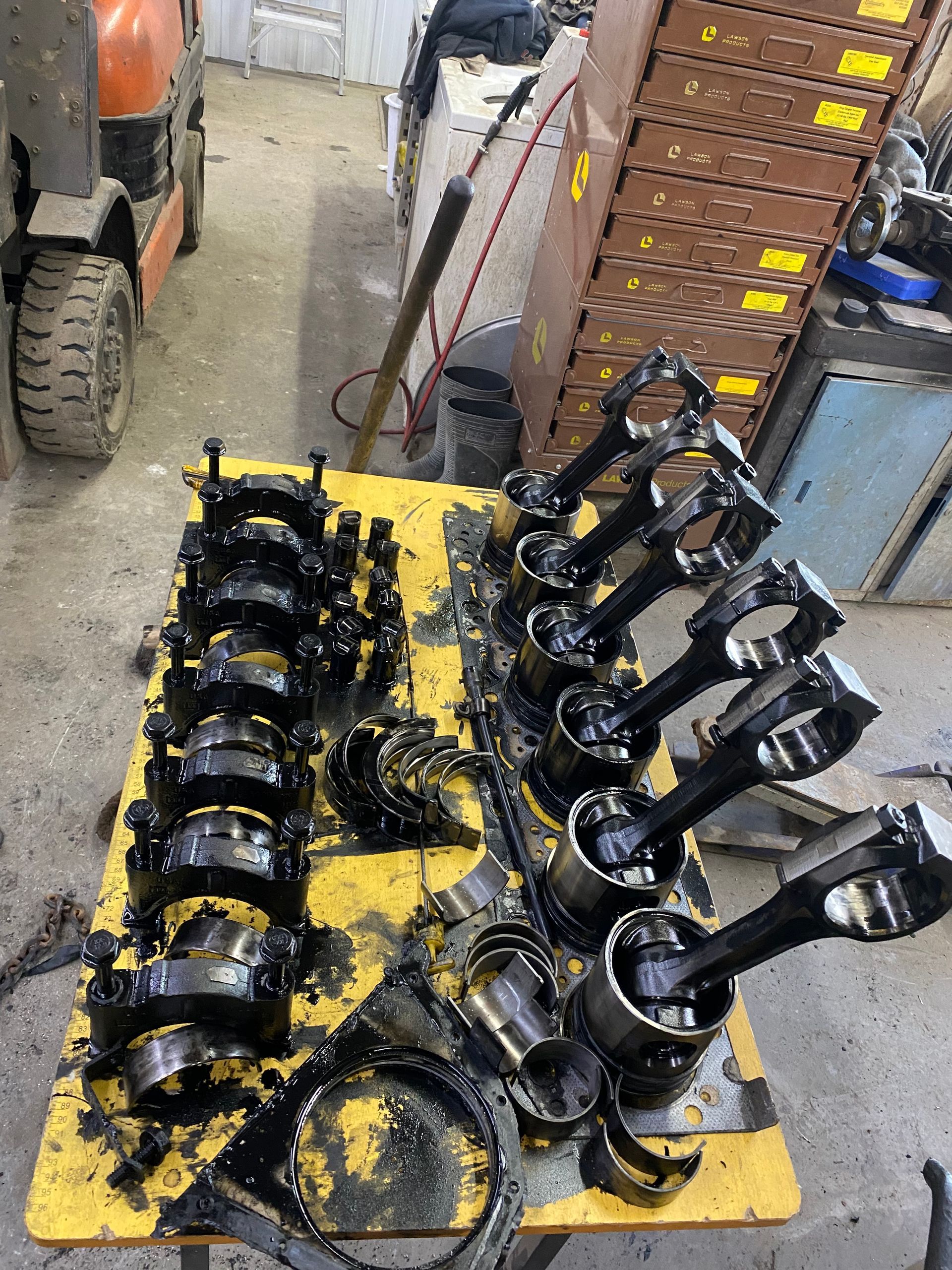 Un tas de pistons sont posés sur une table dans un garage.