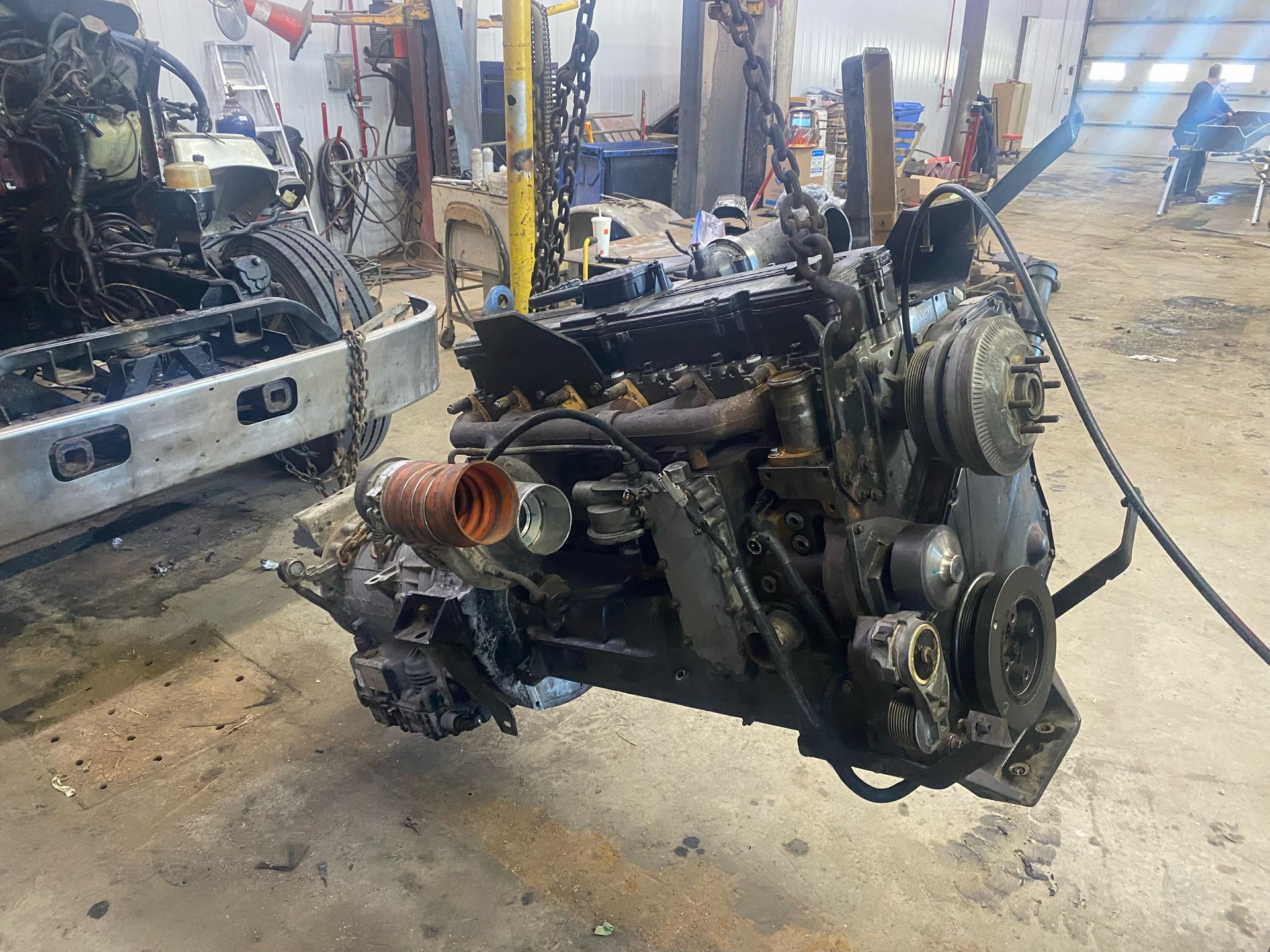 Un gros moteur est en train d'être démonté dans un garage.