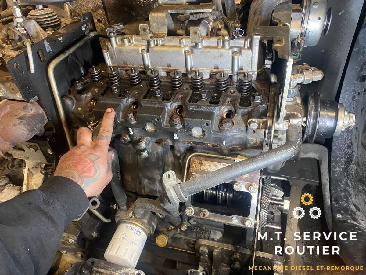 Un homme pointe du doigt le moteur d'un tracteur.