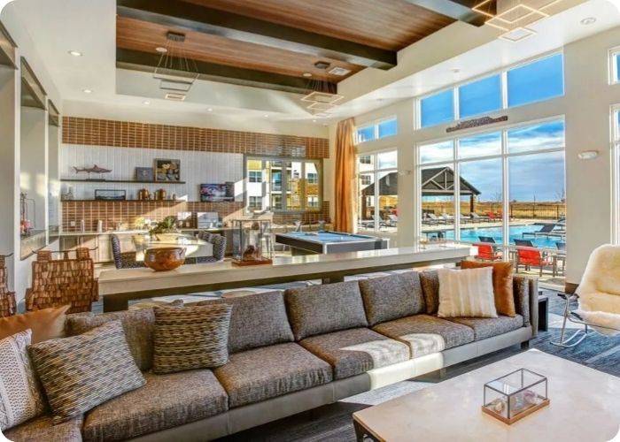Modern living room with gray sectional, wood ceiling, and large windows overlooking water