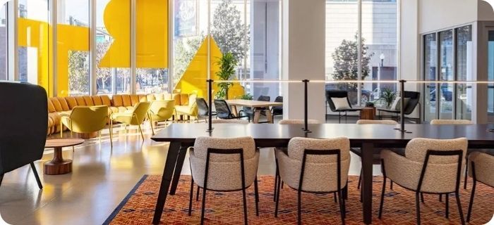Modern meeting room with round tables, white chairs, and yellow accents in a bright office space