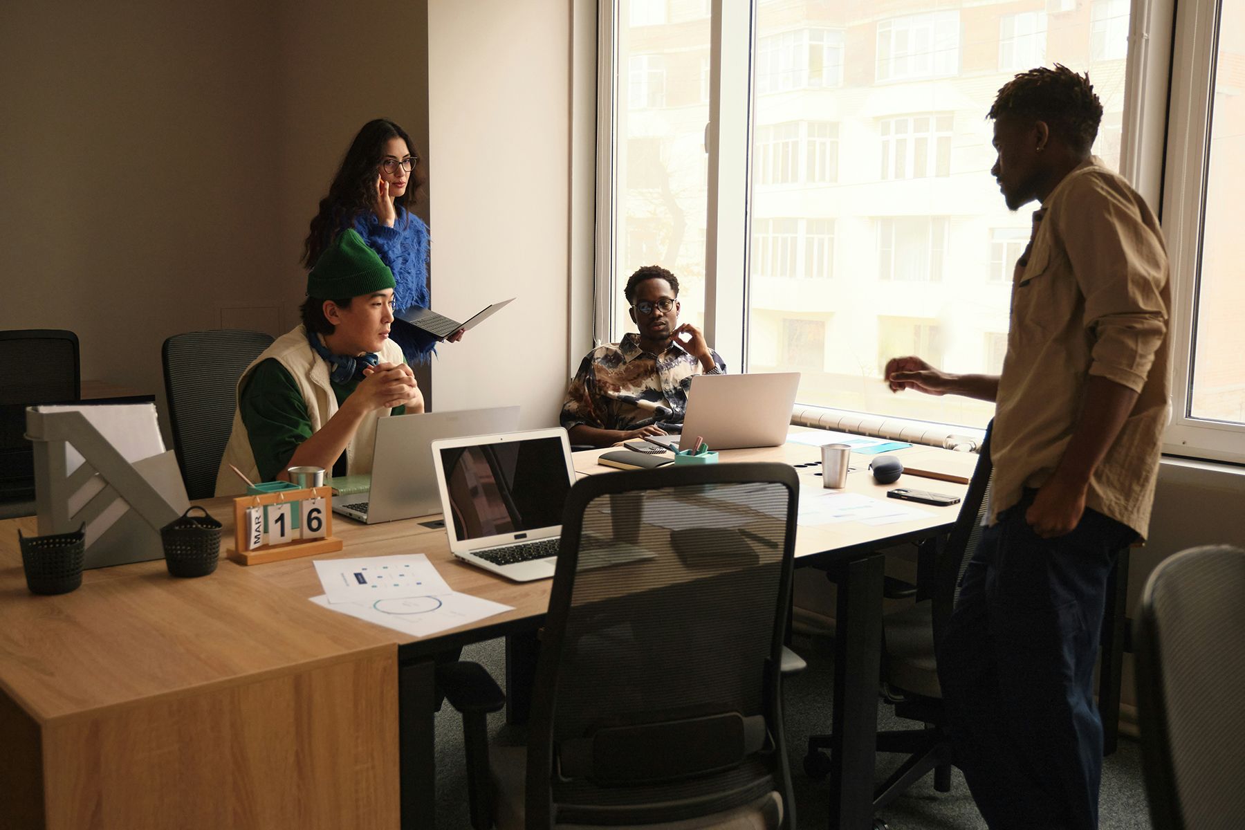 Team meeting in a bright office with four people around a conference table and laptops