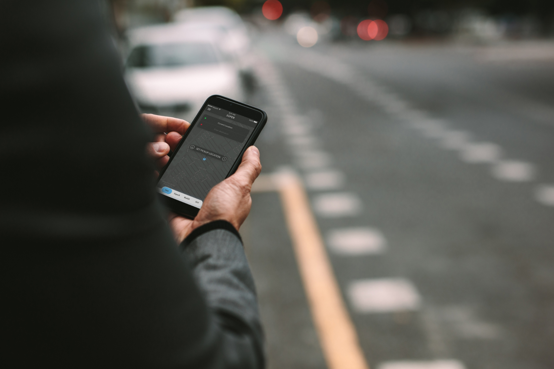 Person holding a smartphone on a blurred city street at dusk