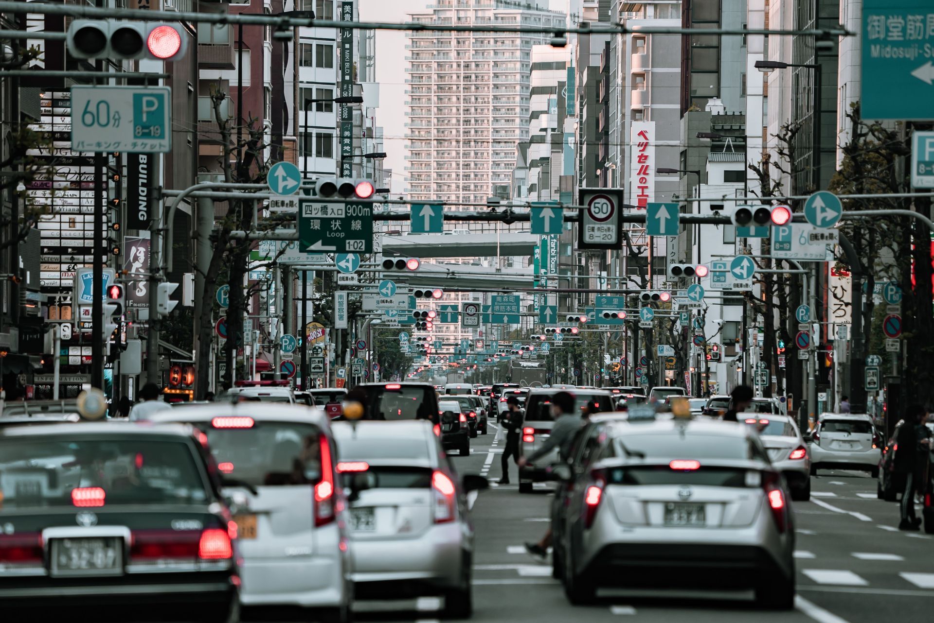 Busy city street with heavy traffic and many cars under traffic lights and tall buildings