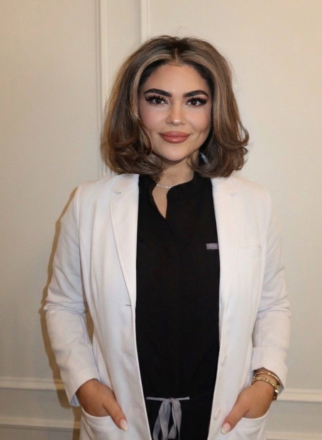 A woman in a gray scrub top and pants is smiling for the camera.