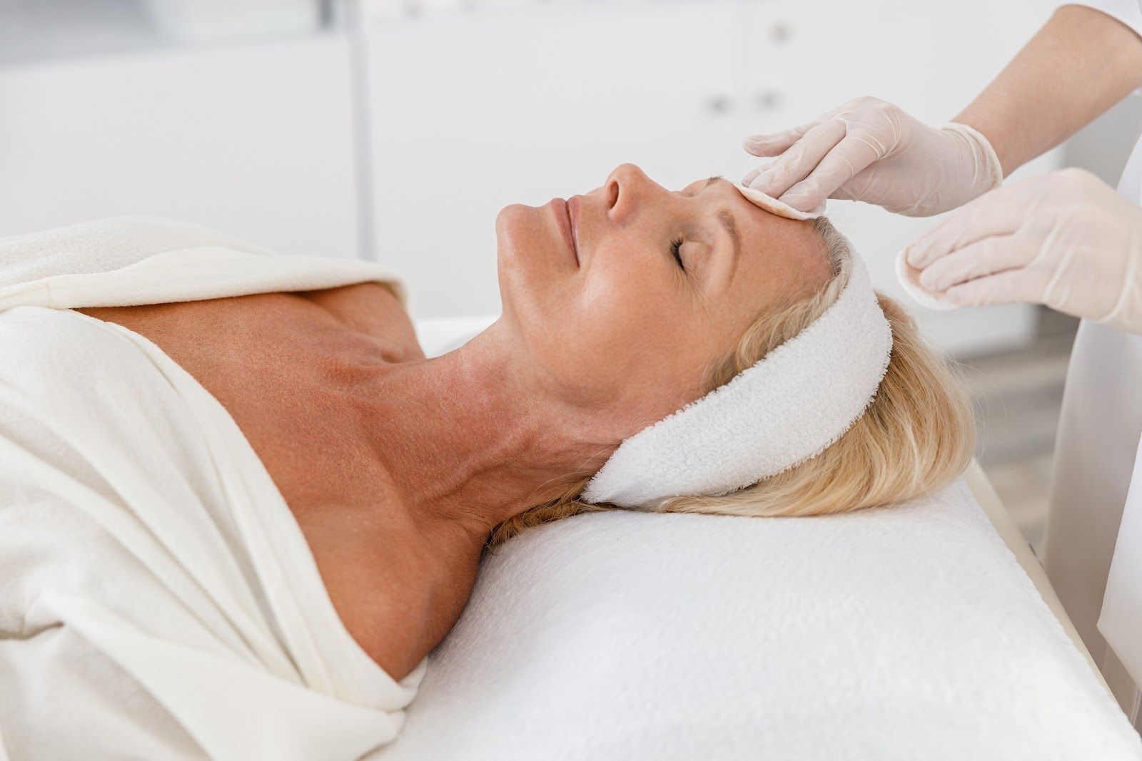 Woman receiving a facial treatment with gloved hands in a spa setting