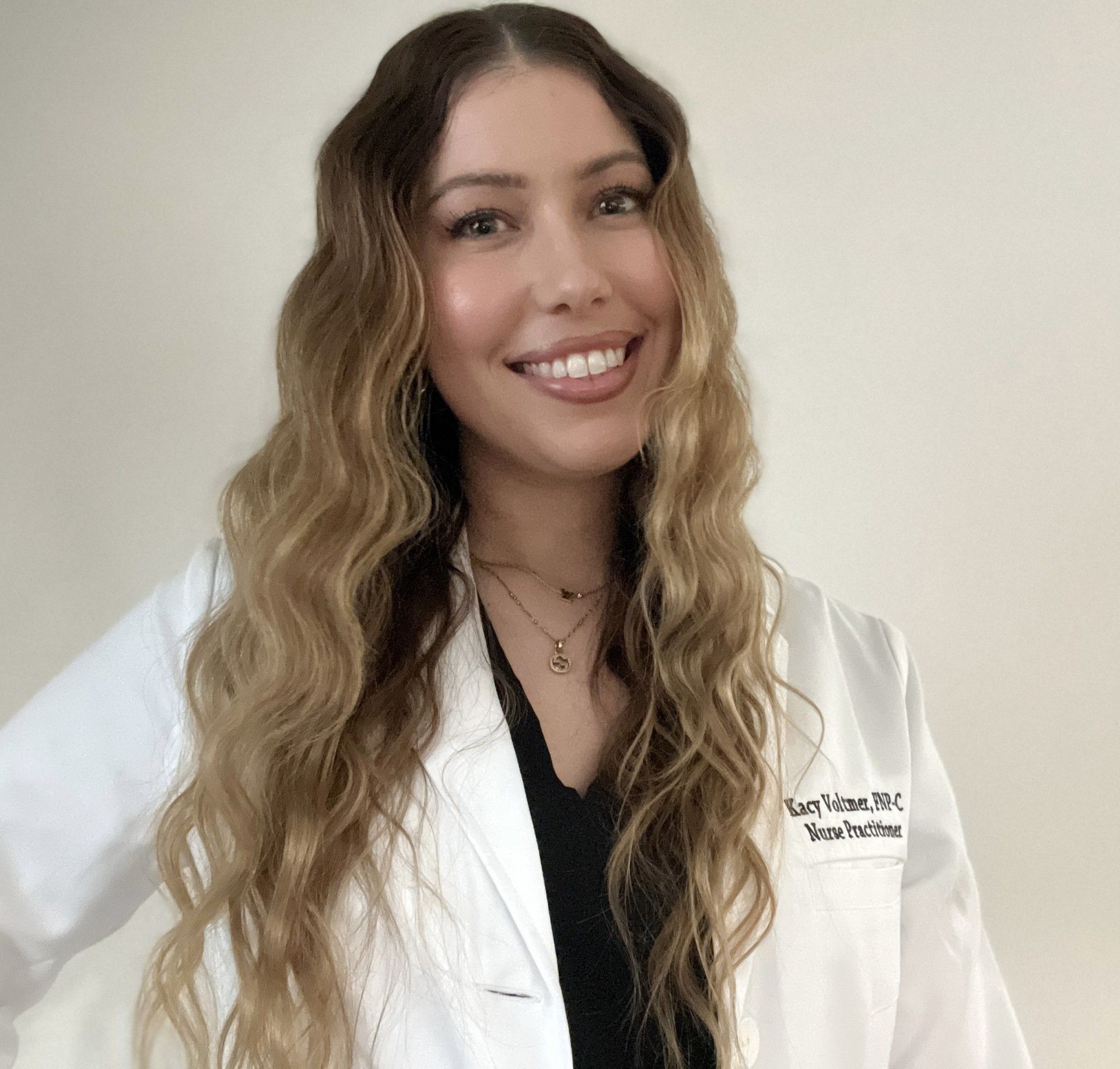 A woman in a white lab coat is smiling for the camera