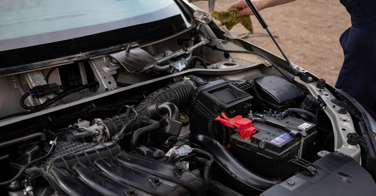 Compartimento del motor del coche con el capó abierto, mostrando la batería y el cableado.