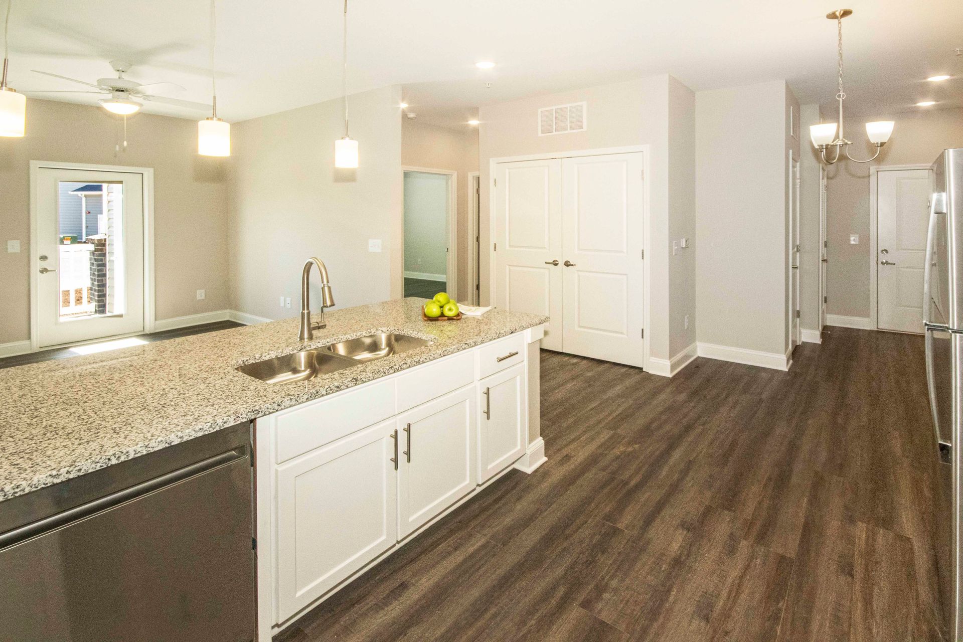 A kitchen with granite counter tops , stainless steel appliances , and hardwood floors.