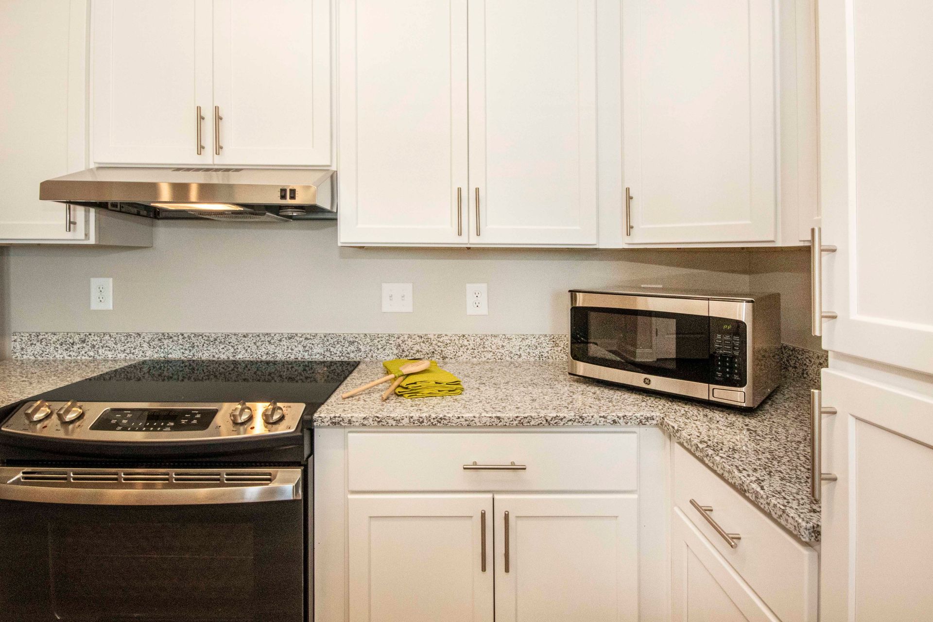 A kitchen with a stove , microwave , and white cabinets.