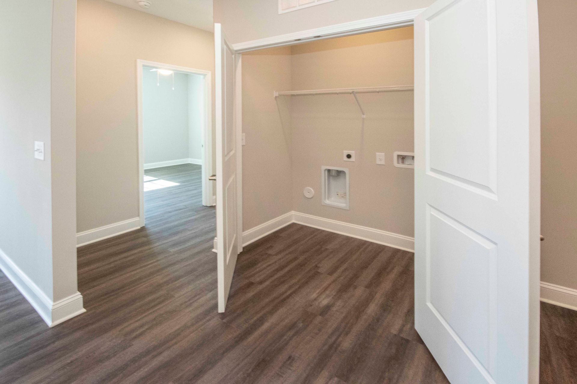 A laundry room in a house with wooden floors and a washer and dryer.