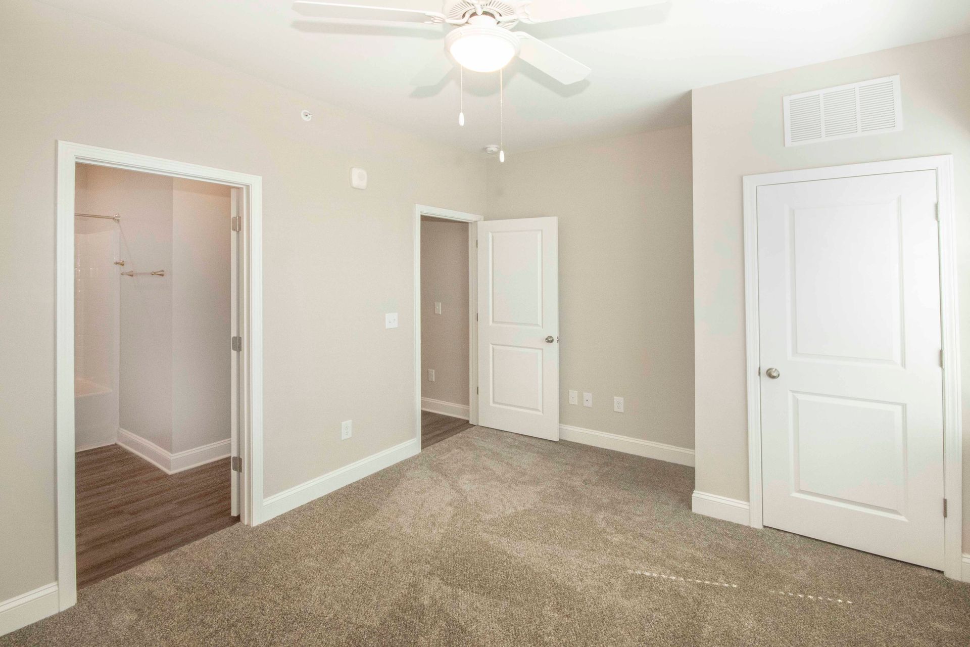 An empty bedroom with a ceiling fan and a walk in closet.