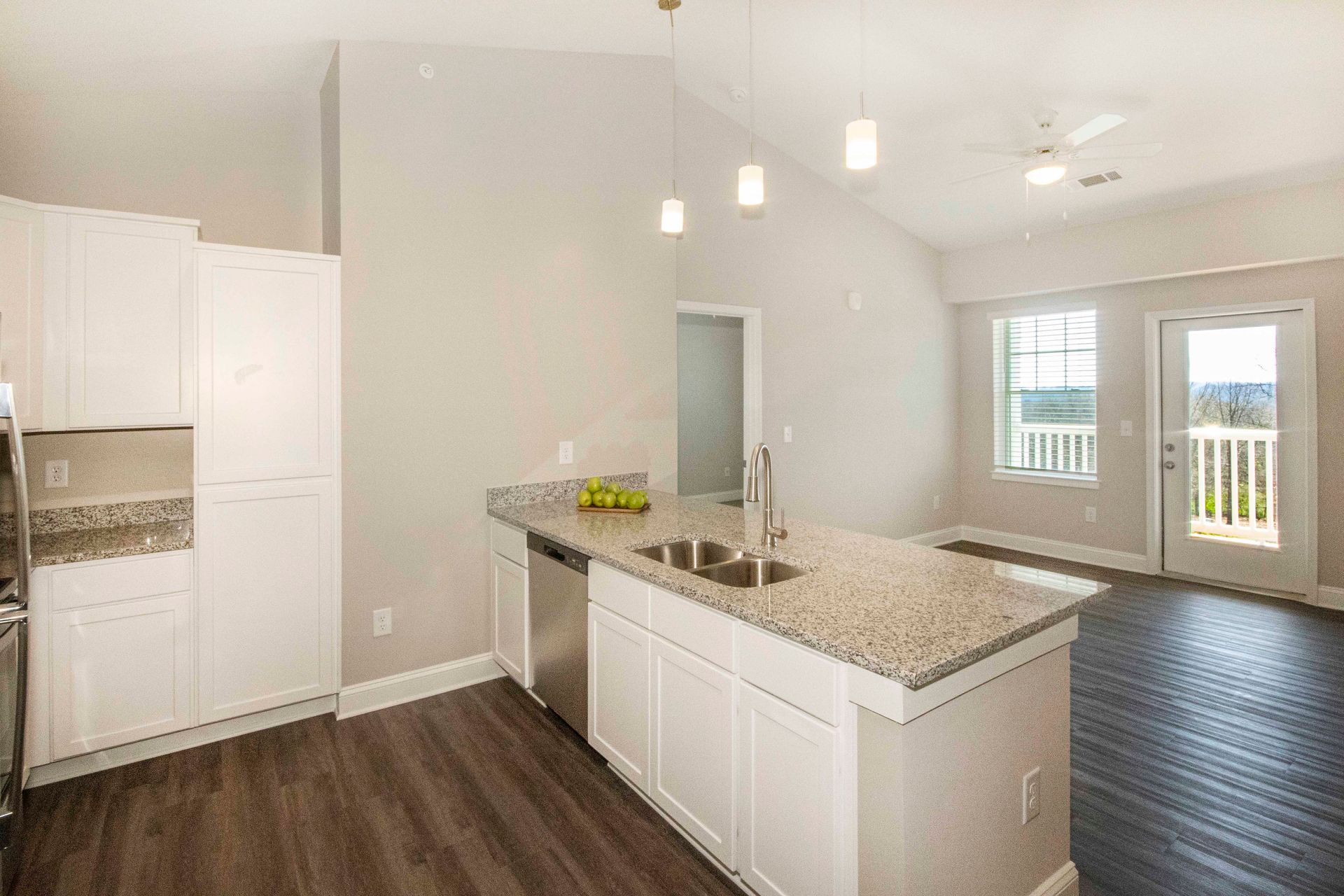 A kitchen with granite counter tops , white cabinets , stainless steel appliances and a large island.