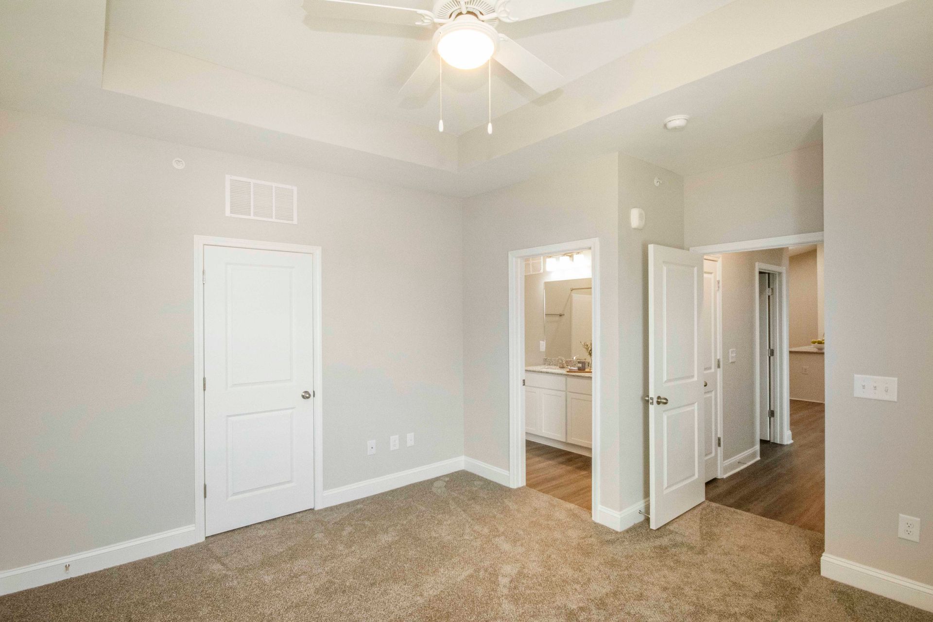 An empty bedroom with a ceiling fan and a bathroom.