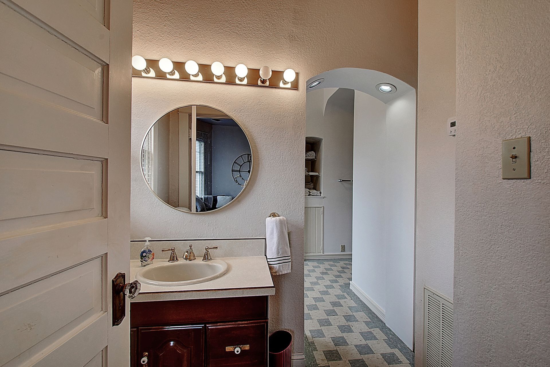 A bathroom with a sink and a round mirror