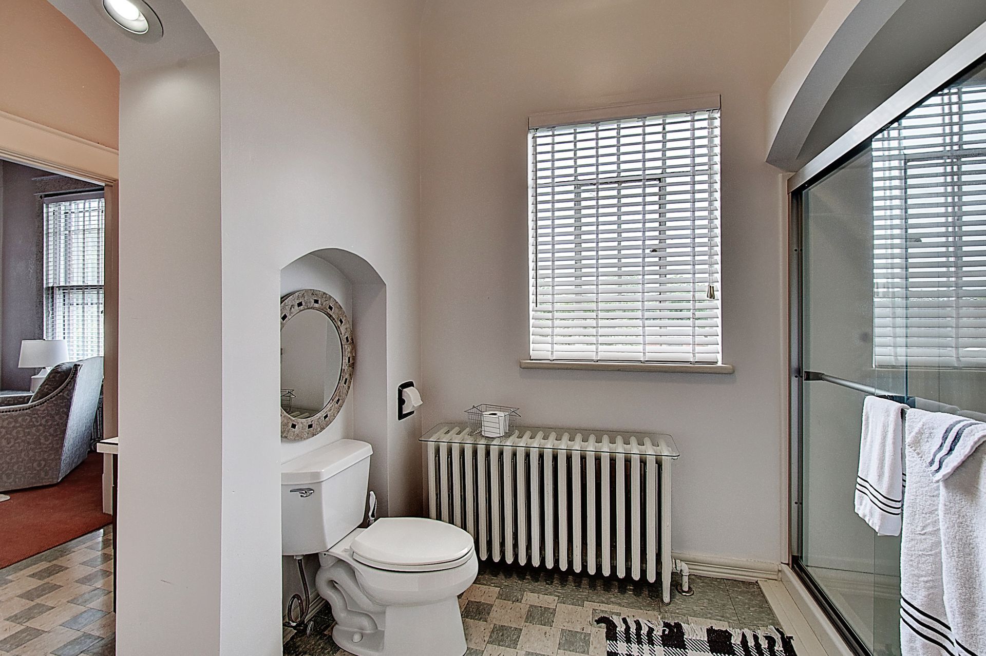 A bathroom with a toilet , sink , mirror and window.