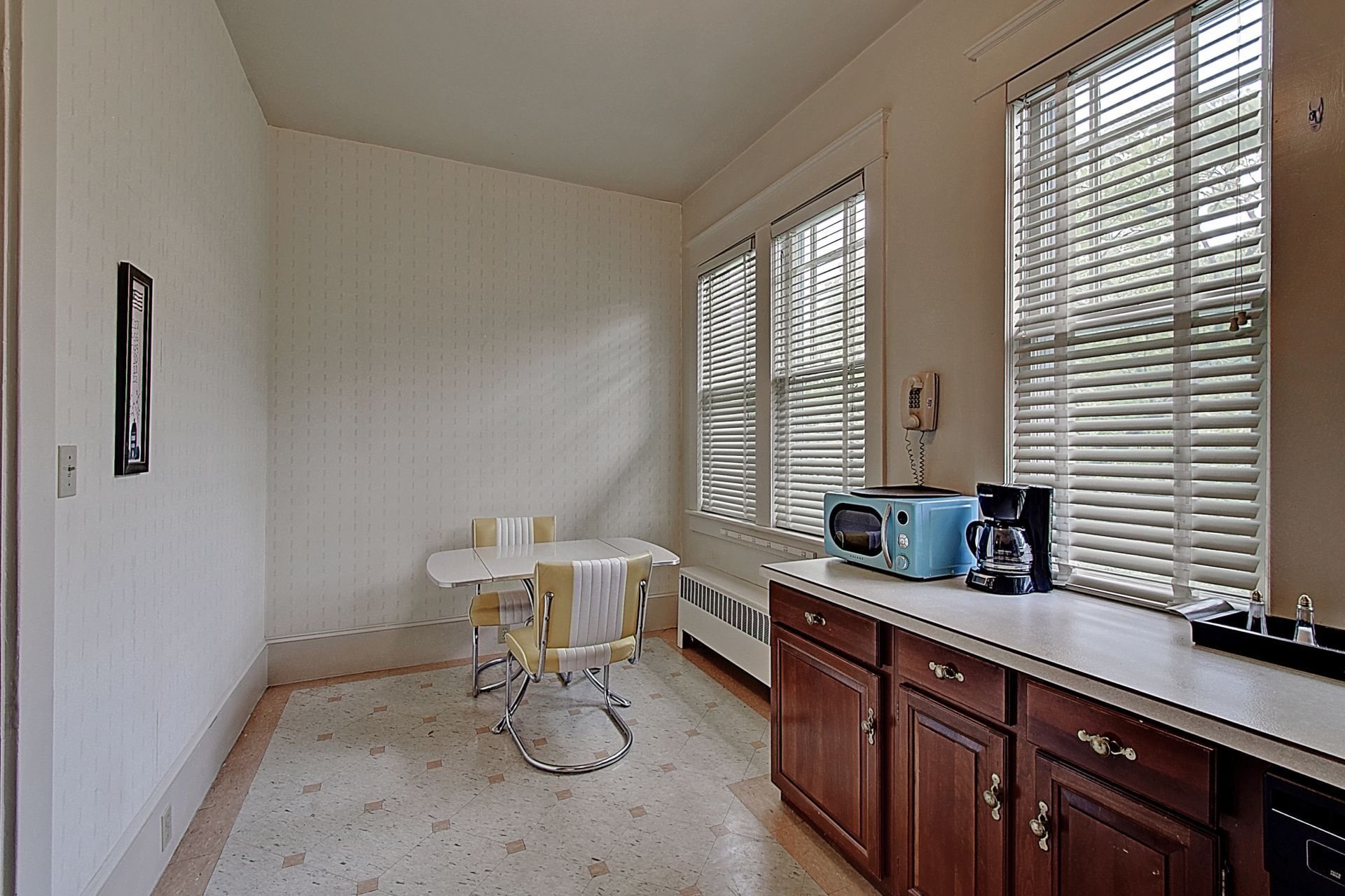 A kitchen with a table and chairs and blinds on the windows