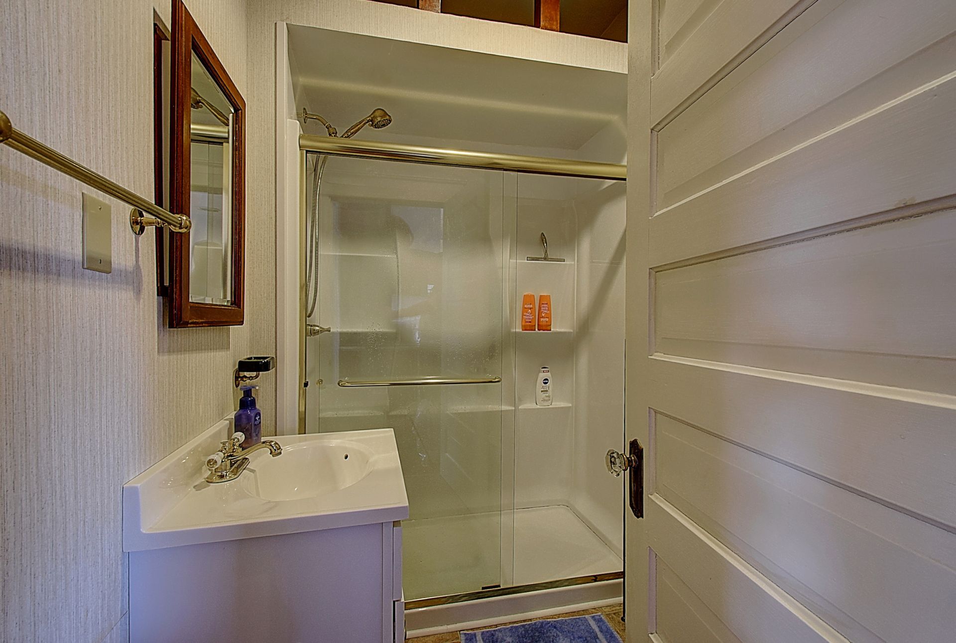 A bathroom with a sink and a walk in shower.