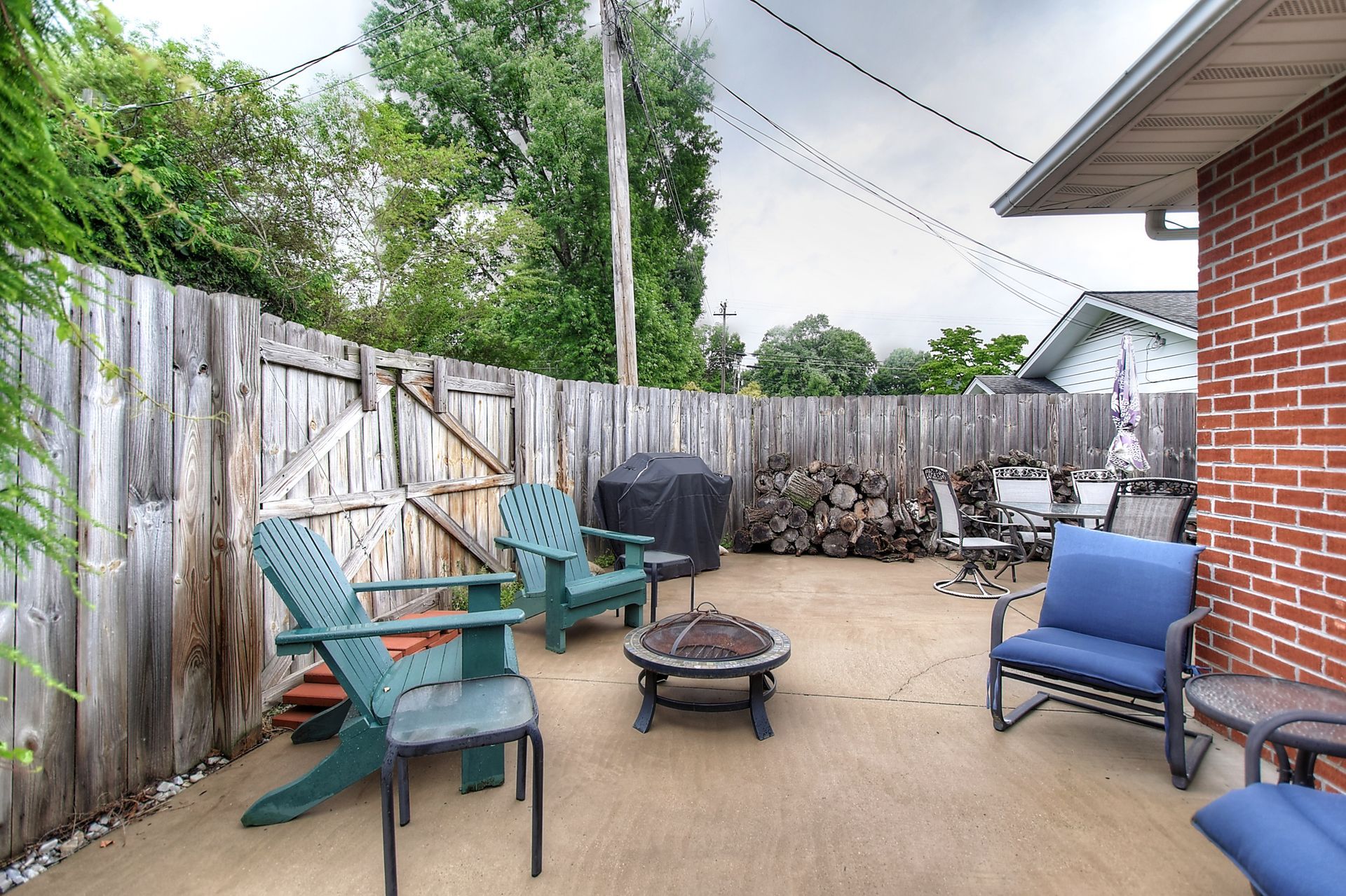 A patio with chairs and a fire pit in front of a brick house