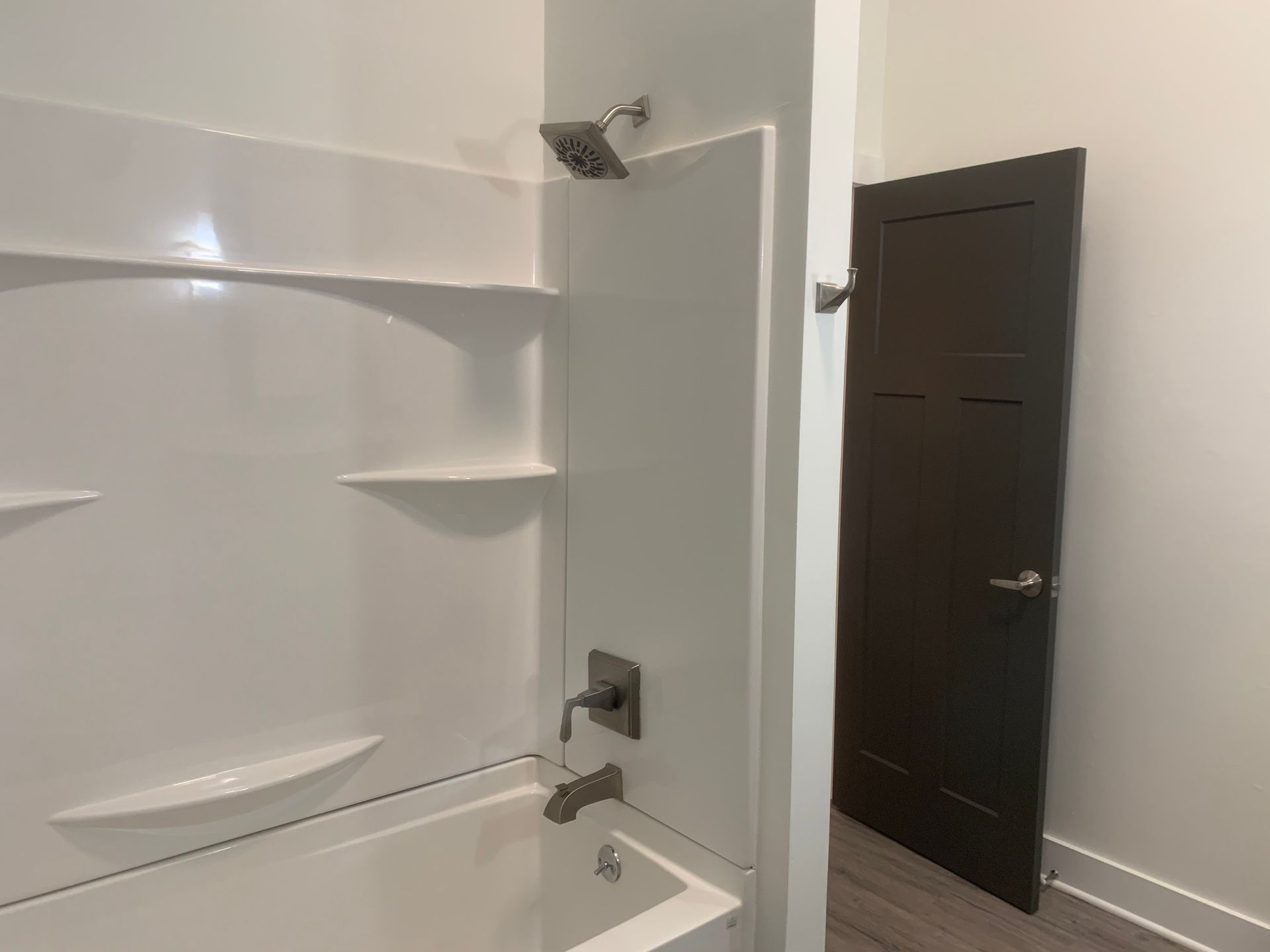 A bathroom with a bathtub , shower , and shelves.