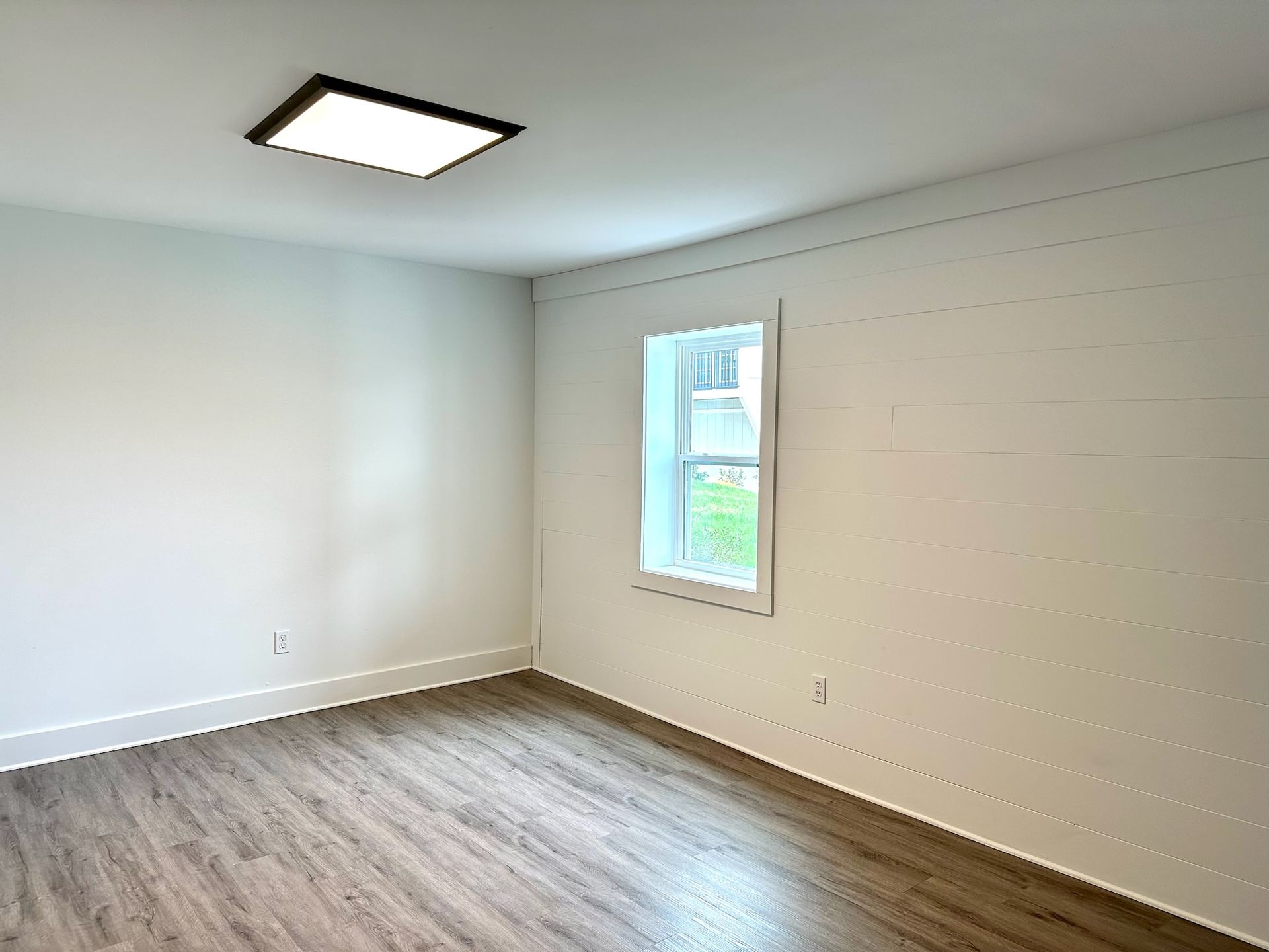 An empty room with hardwood floors and a window.