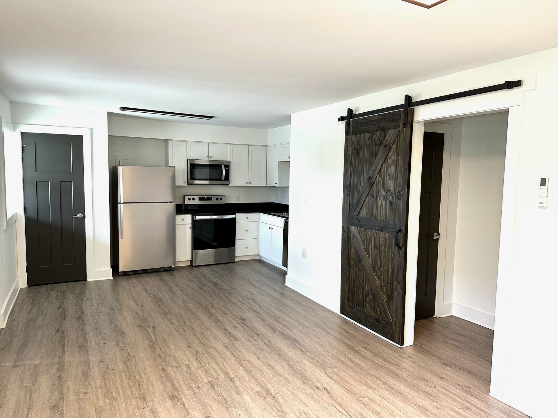 A living room with a sliding barn door leading to a kitchen.