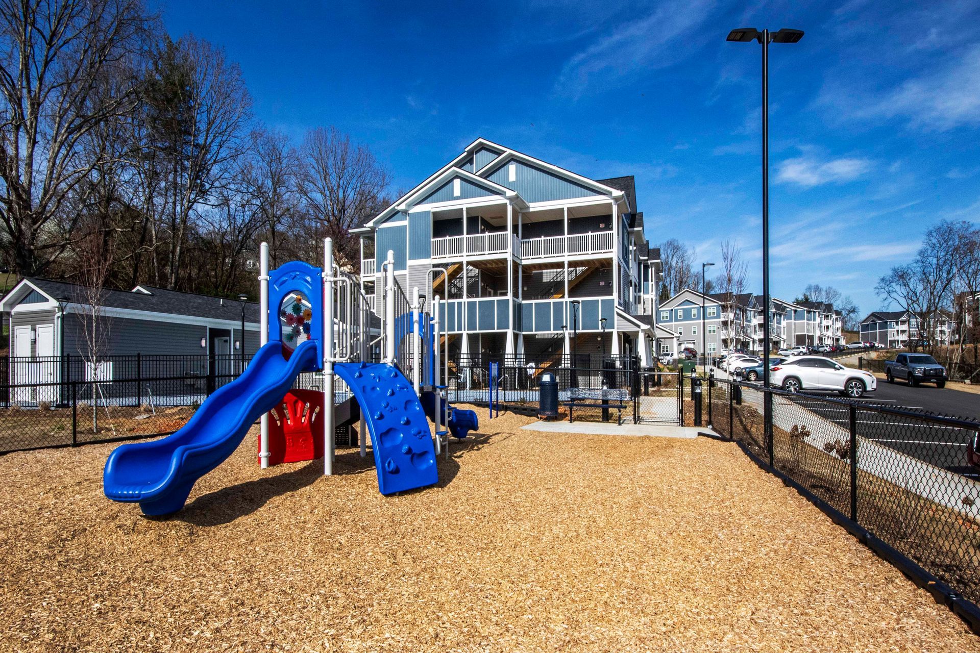 A blue playground with a slide in front of a building.